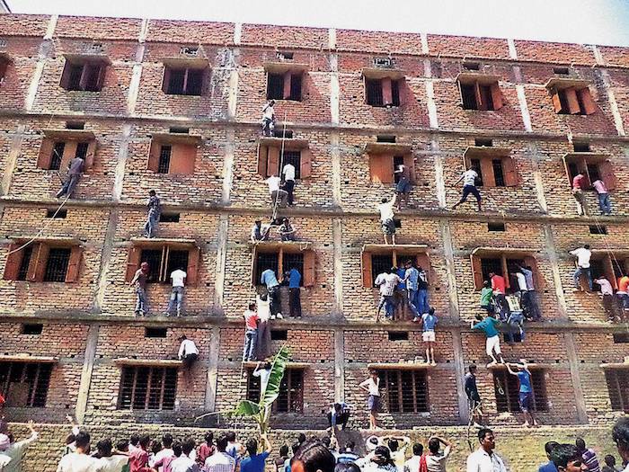 Youths climbing the building of an examination centre to help the candidates in cheating, by passing notes through the windows, during a Matriculation examination in Hajipur, Bihar in 2015