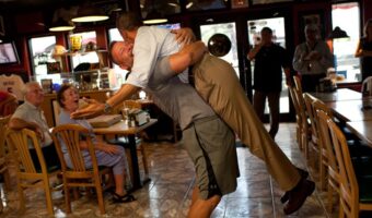 President Obama is lifted in the air by Scott Van Duzer, owner of the Big Apple Pizza owner
